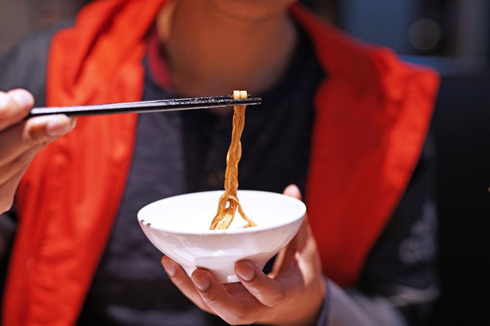 close-up photography of man using chopsticks on pasta