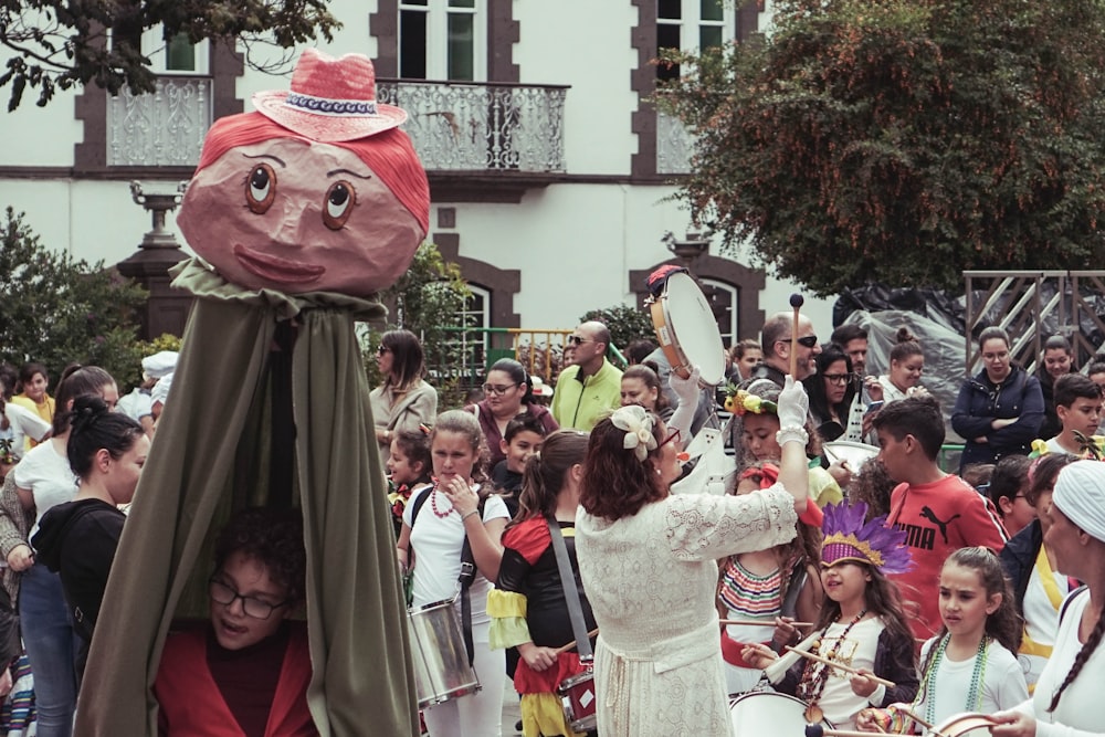 girls carrying drums beside boy carrying costume