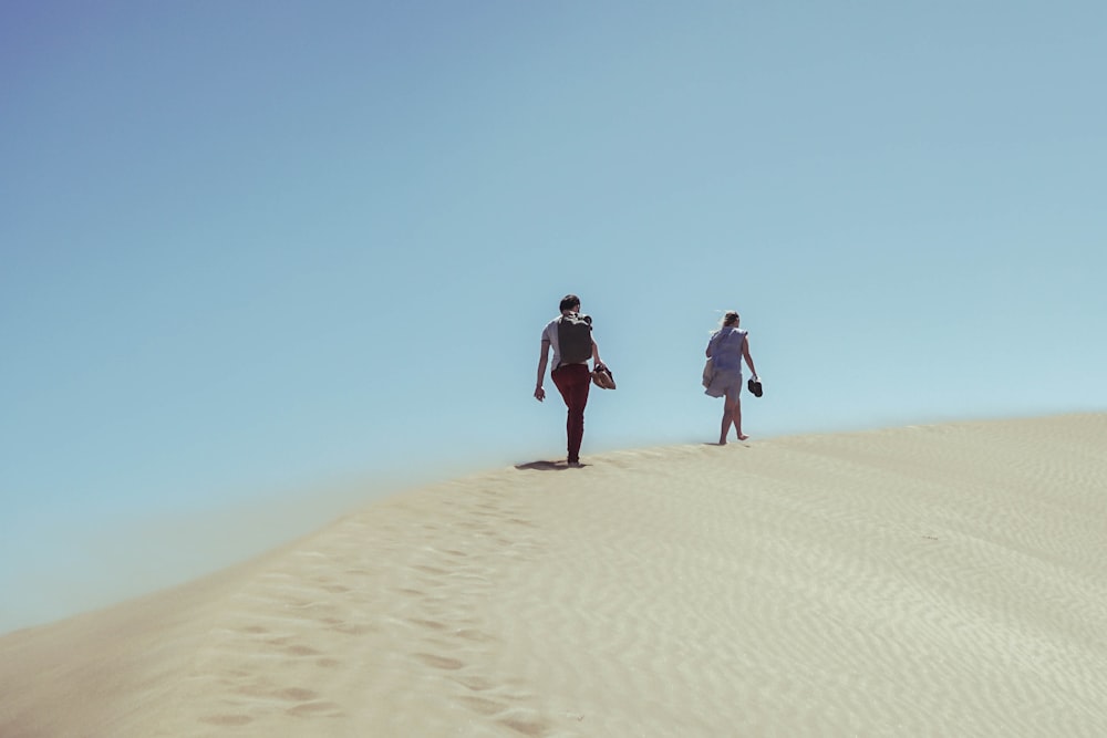 two persons walking on desert during daytime