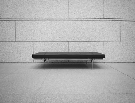 Banc en cuir noir devant un mur en brique grises