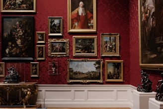 An elegant gallery wall with framed old paintings and classic art pieces in golden frames.
