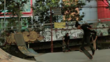 A skateboarder performing a trick on an urban street with graffiti walls.