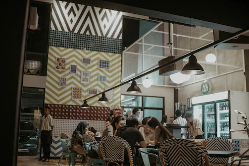A diverse group laughing together inside a warmly lit modern cafe.