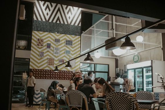 A vibrant group of young people studying and sharing ideas in a cozy, colorful cafe setting.