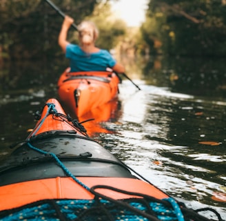selective focus photography of woman riding kayak holding oar during daytime