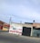 A mural on a concrete wall displays colorful text reading 'Viva Mexico Viva Morena' in bold green and red letters. The wall is situated along a street, with surrounding buildings made of brick and concrete. Power lines stretch across the sky above the structures.