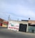 A mural on a concrete wall displays colorful text reading 'Viva Mexico Viva Morena' in bold green and red letters. The wall is situated along a street, with surrounding buildings made of brick and concrete. Power lines stretch across the sky above the structures.