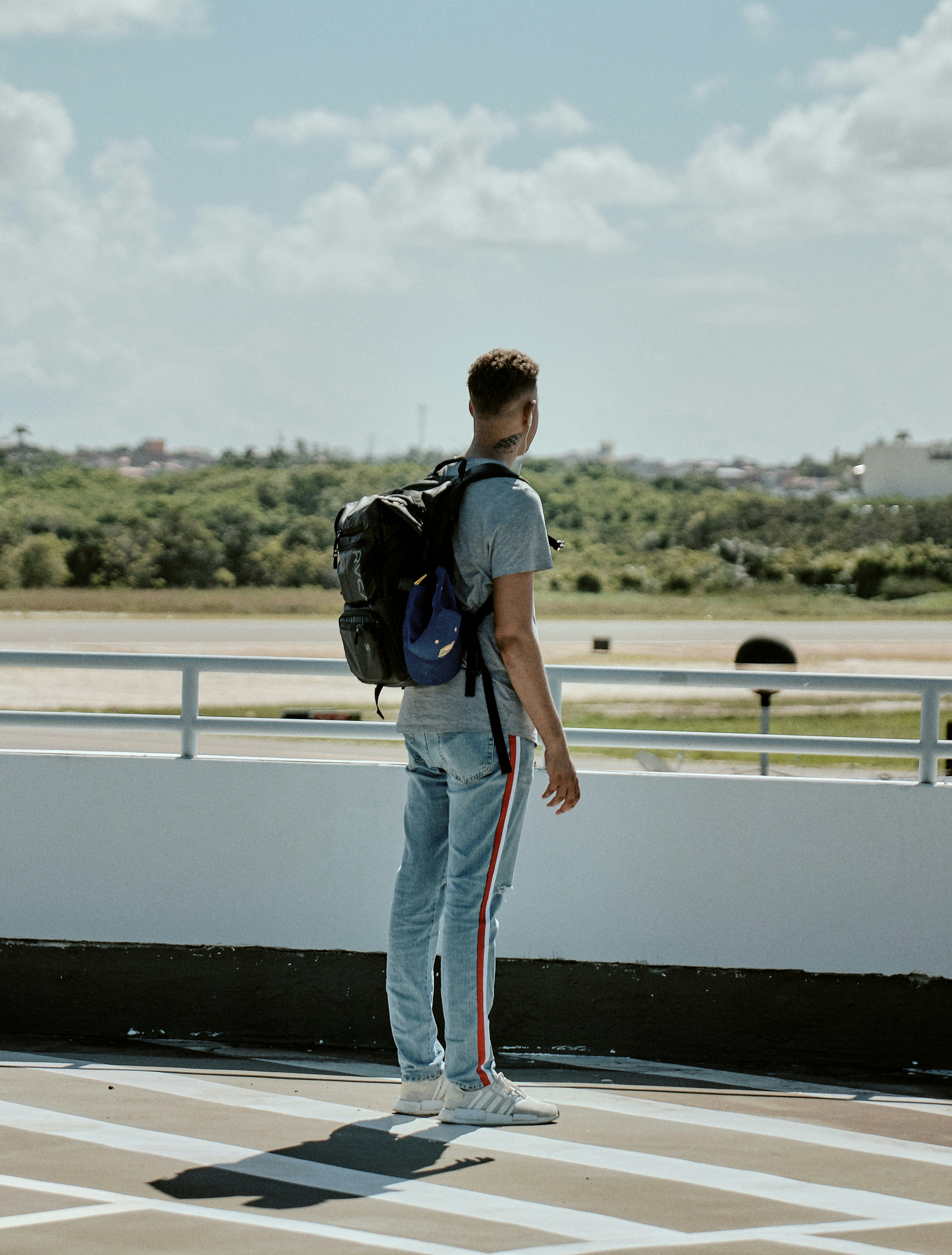 homem com mochila preta fica de frente para a estrada