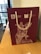 A maroon gift bag with white rope handles. The bag features a detailed drawing of an equestrian statue and logos for the Moscow City Government and Department for External Economic and International Relations. It is placed on a wooden table near a window with buildings visible outside.