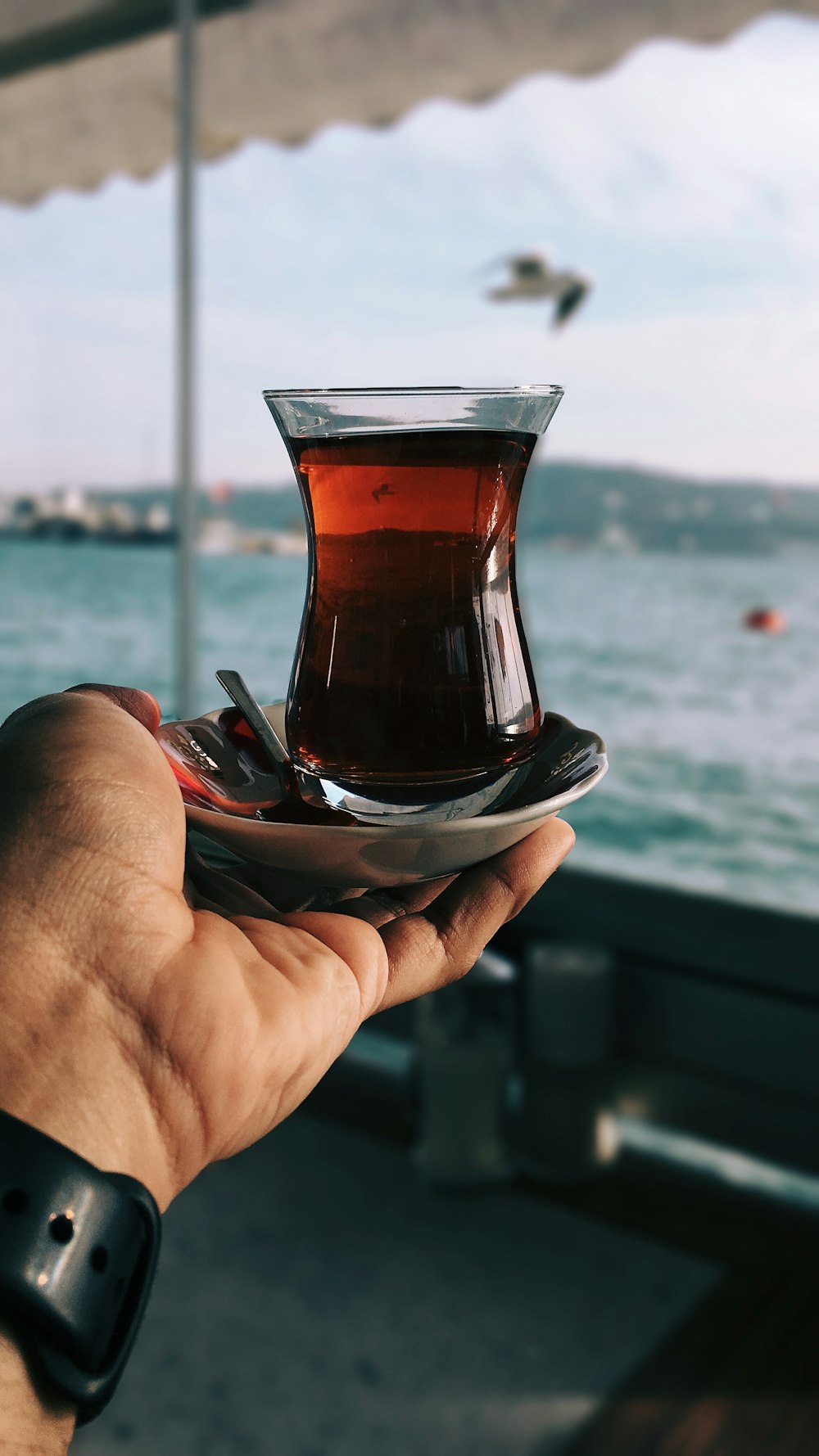 Copo de chá turco na palma da mão da pessoa
