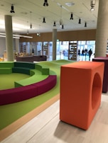 Interactive learning area with colorful cushions and tech devices for the Trilha Atípica.