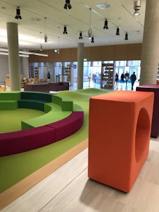 Bright community room with sage green walls and rounded seating arrangements.