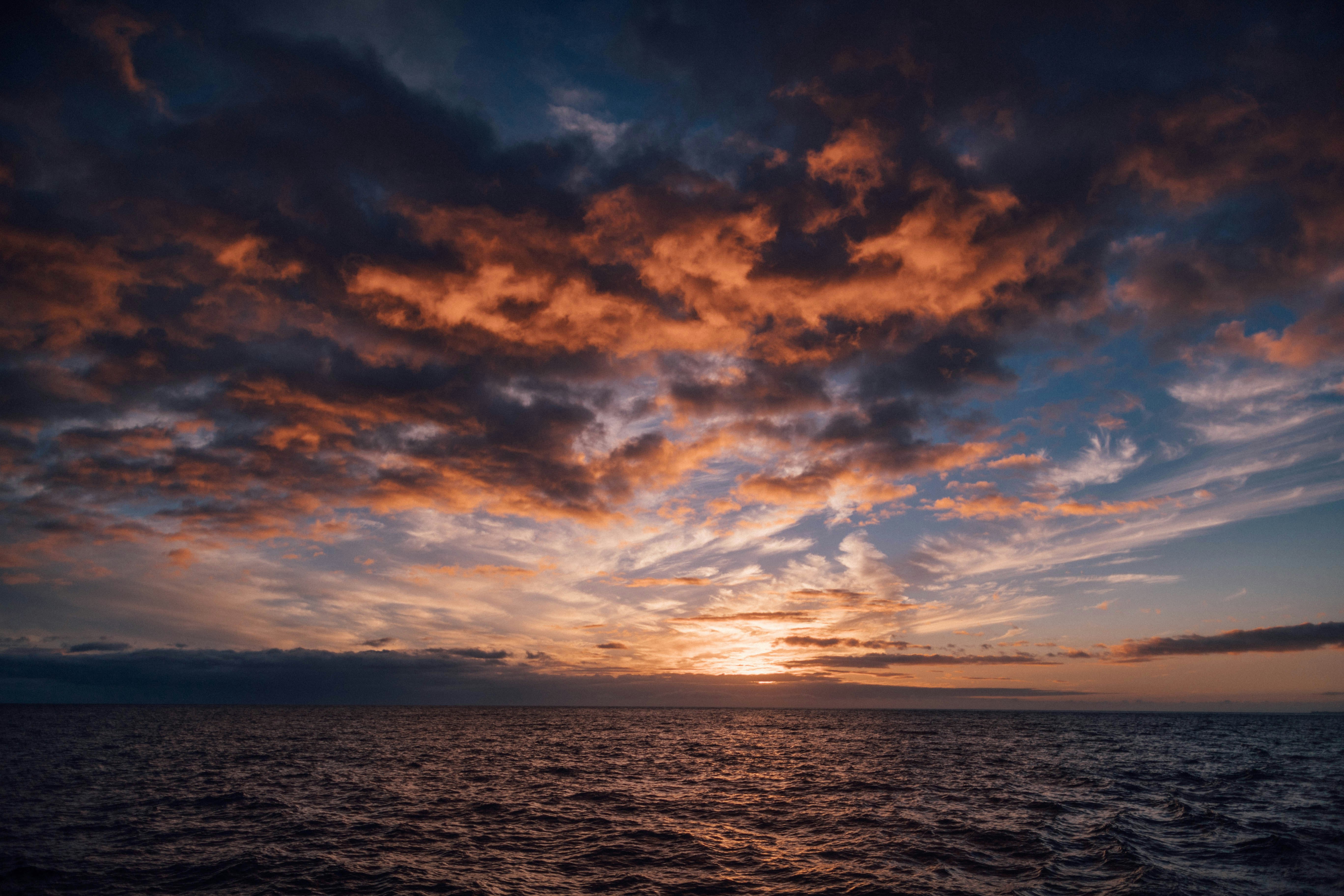 orange and grey clouds over sea at dusk