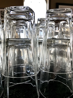 Stack of transparent polypropylene tumblers with a subtle green tint reflecting light.