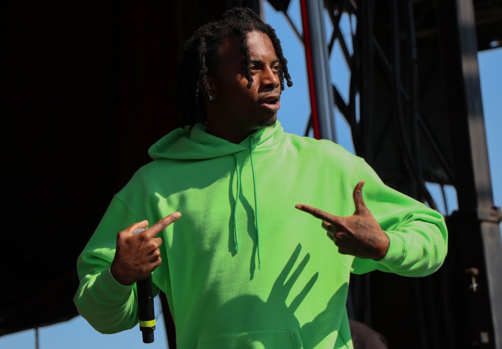 a man in a green hoodie pointing at something