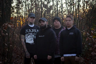 A group of fathers walking together at dawn, united in faith and purpose along a wooded path.