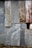 An assortment of corrugated metal sheets, weathered and rusted, are patched together to form a wall. The surface features a mix of textures and hues, with visible signs of aging and corrosion.