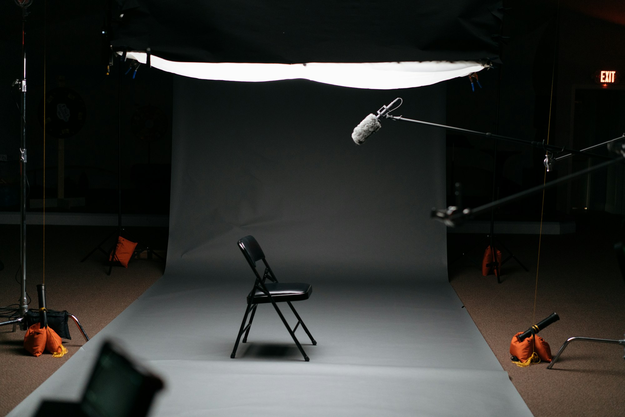 A single chair sits in a fully-lit recording set, complete with lights and microphones.