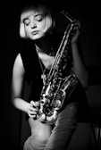 grayscale photography of woman holding saxophone