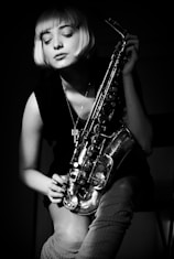 grayscale photography of woman holding saxophone
