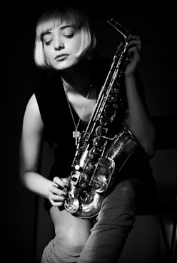 grayscale photography of woman holding saxophone
