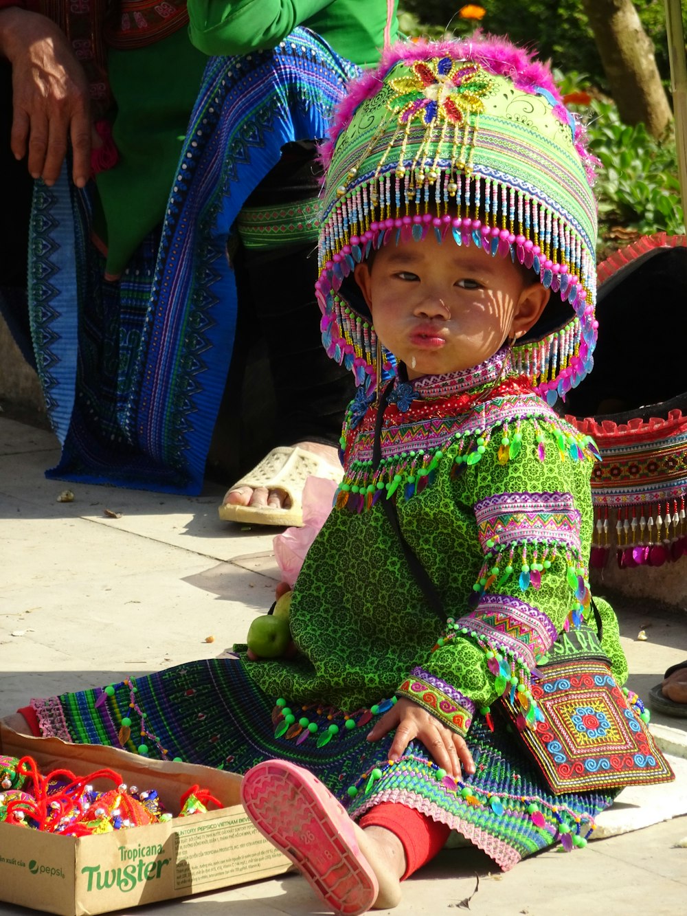 child wearing green and multicolored costume sitting on brown surface