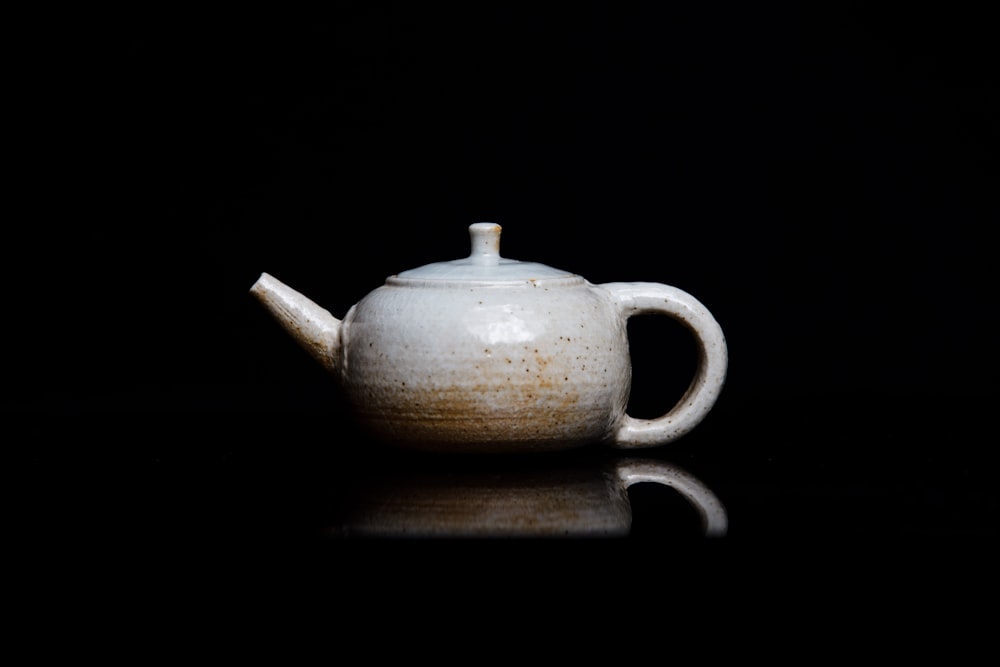 white teapot on black background