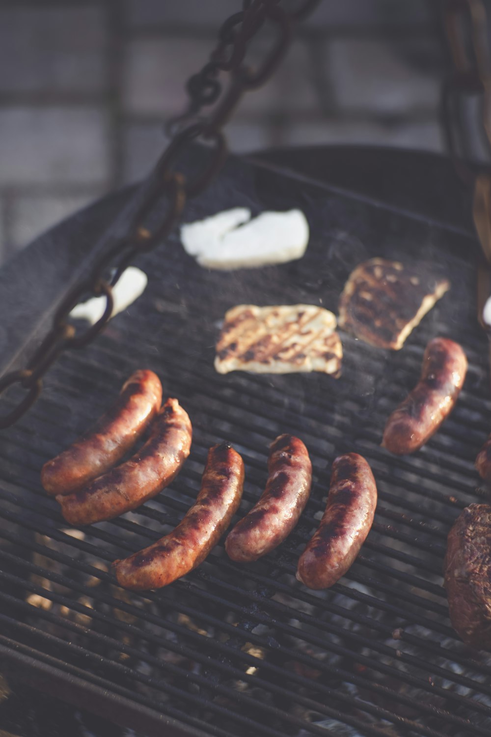 a grill with sausages and other foods cooking on it