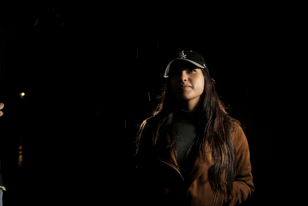 woman in brown jacket and black and grey fitted cap