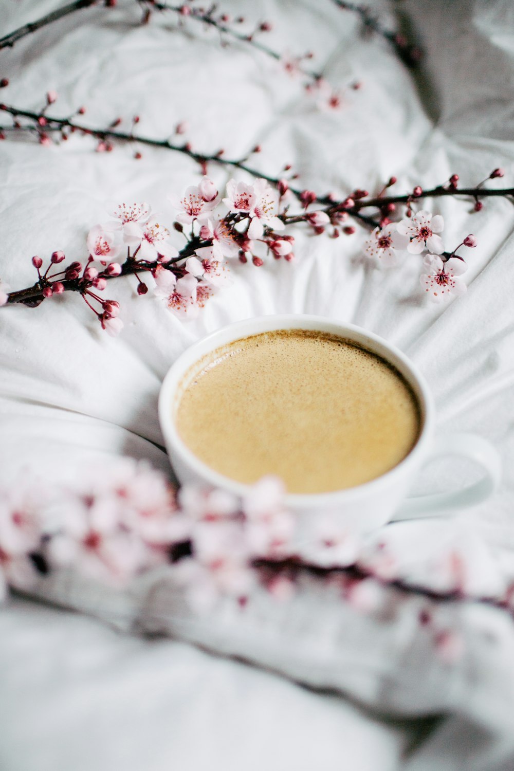 white teacup on white textile