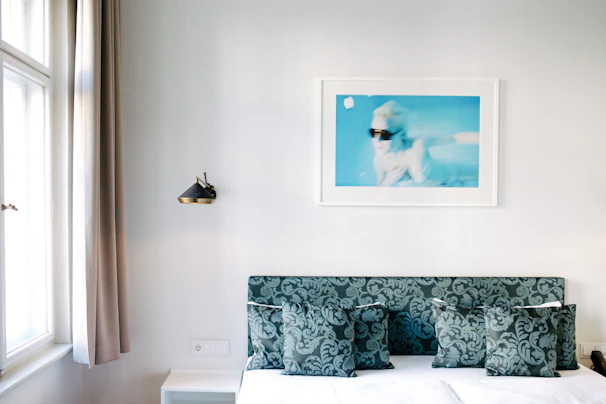 A minimalist bedroom wall adorned with a high-definition metal poster of an abstract art piece glowing under soft lighting.