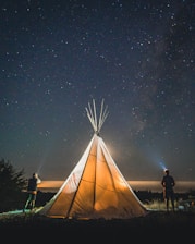 two person standing beside tent during nighttime
