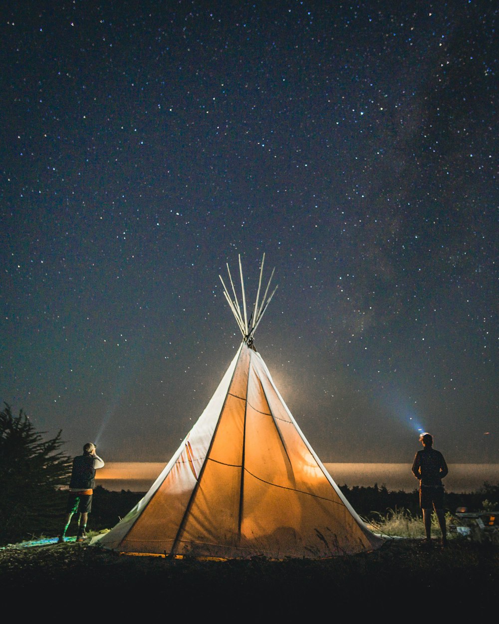 deux personnes debout à côté de la tente pendant la nuit
