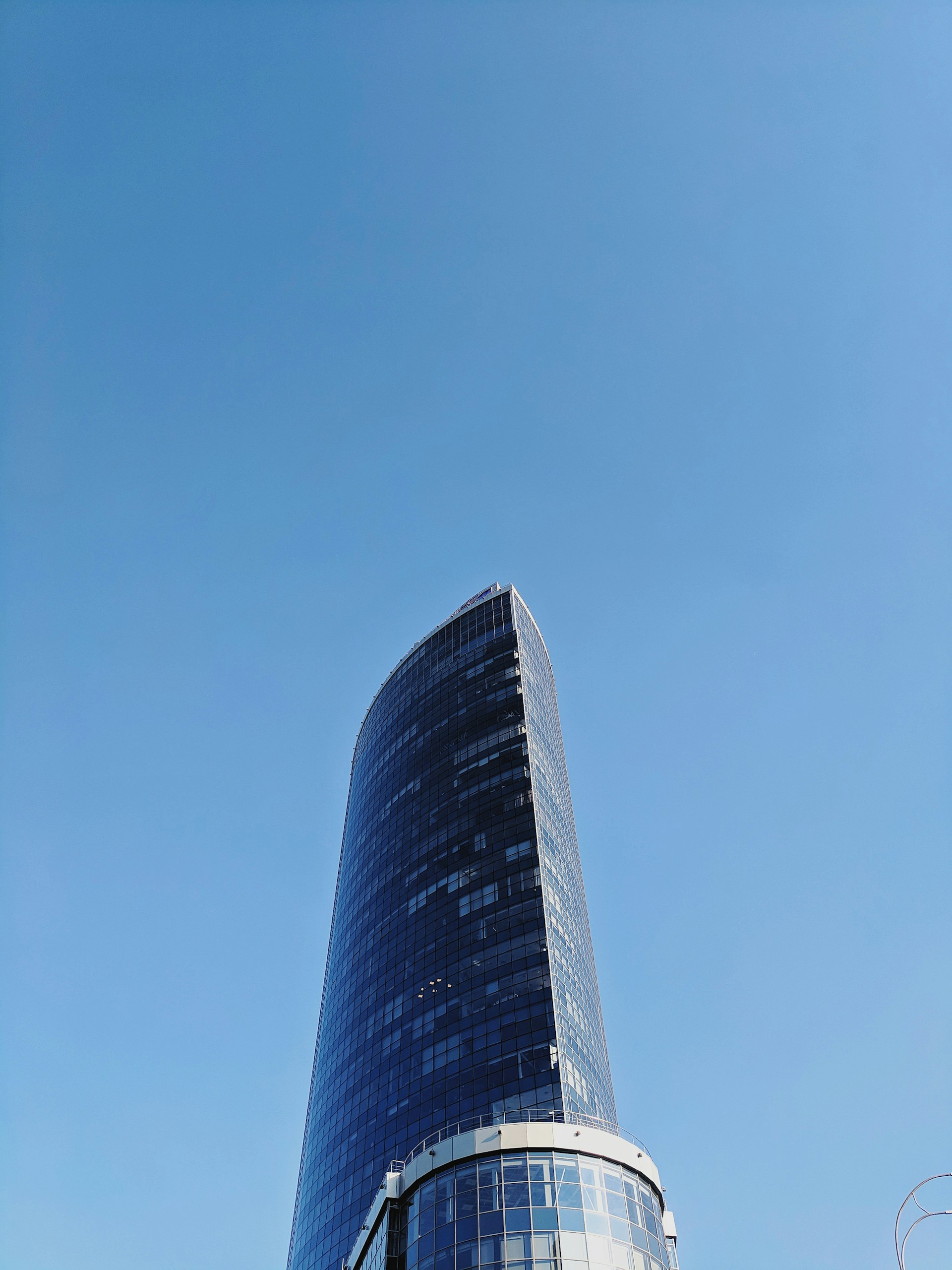 A sleek, modern skyscraper in the UAE gleaming under a clear blue sky, showcasing contemporary architecture.
