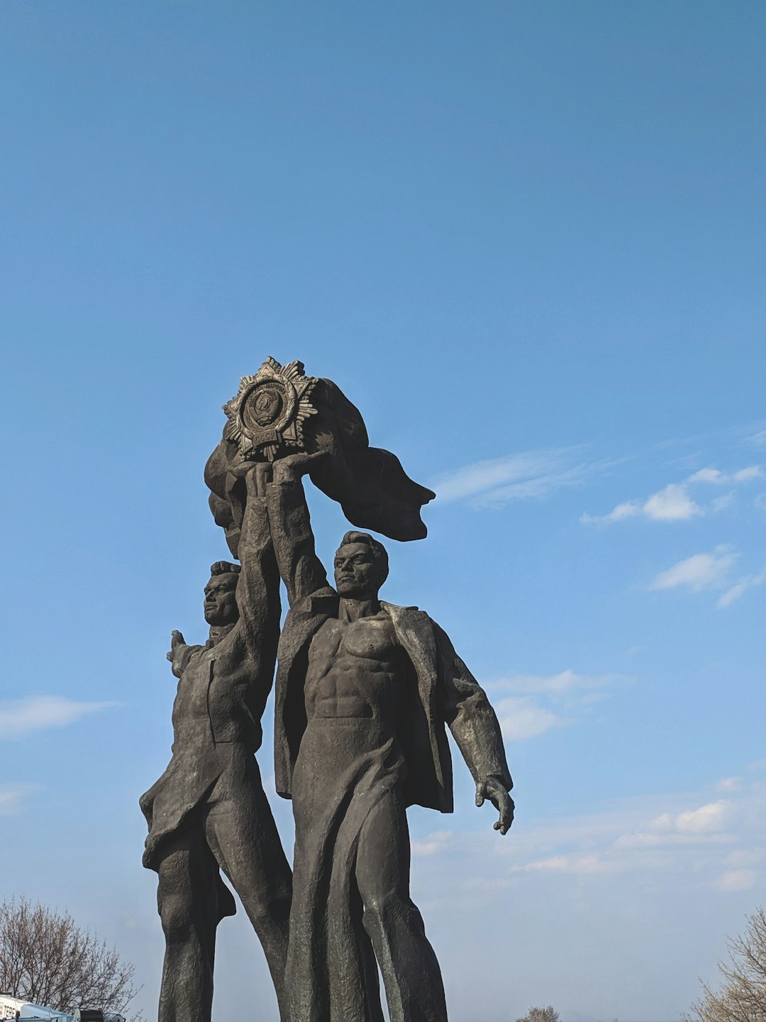 two men raising belt statue under clear blue sky