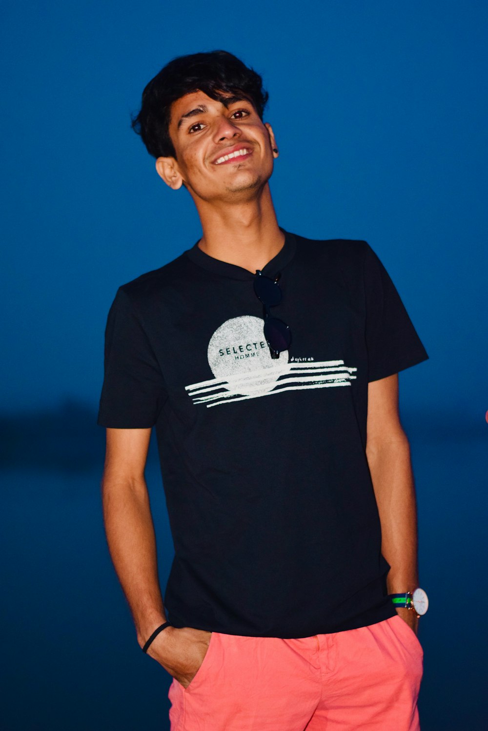 smiling man wearing black and white crew-neck t-shirt and red bottoms