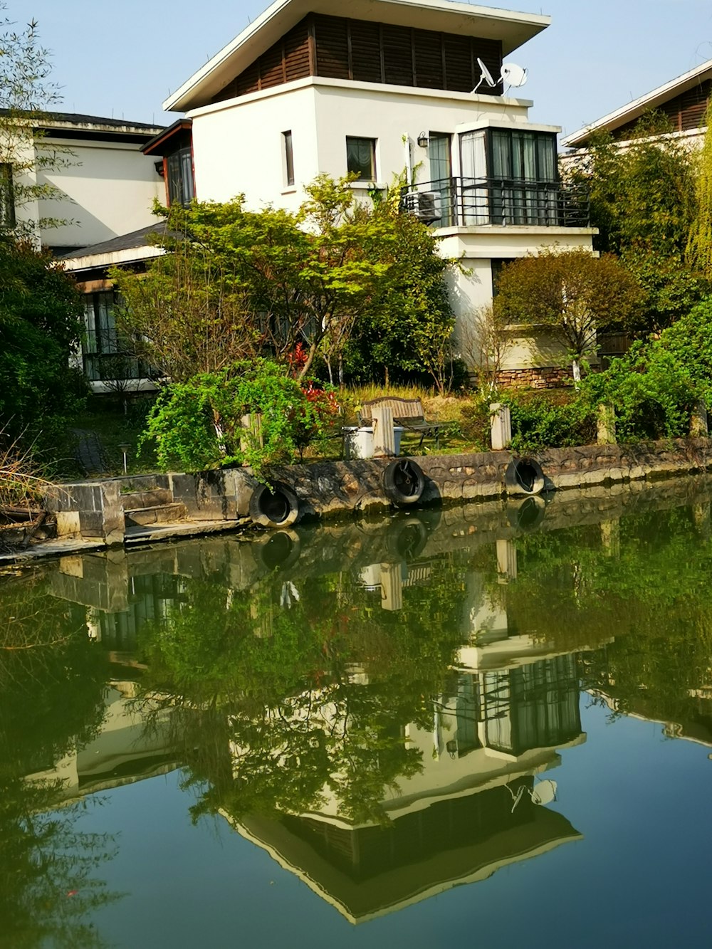 house near plants and body of water during daytime