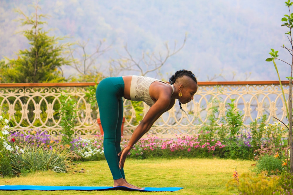 femme portant un pantalon turquoise debout sur un tapis de yoga