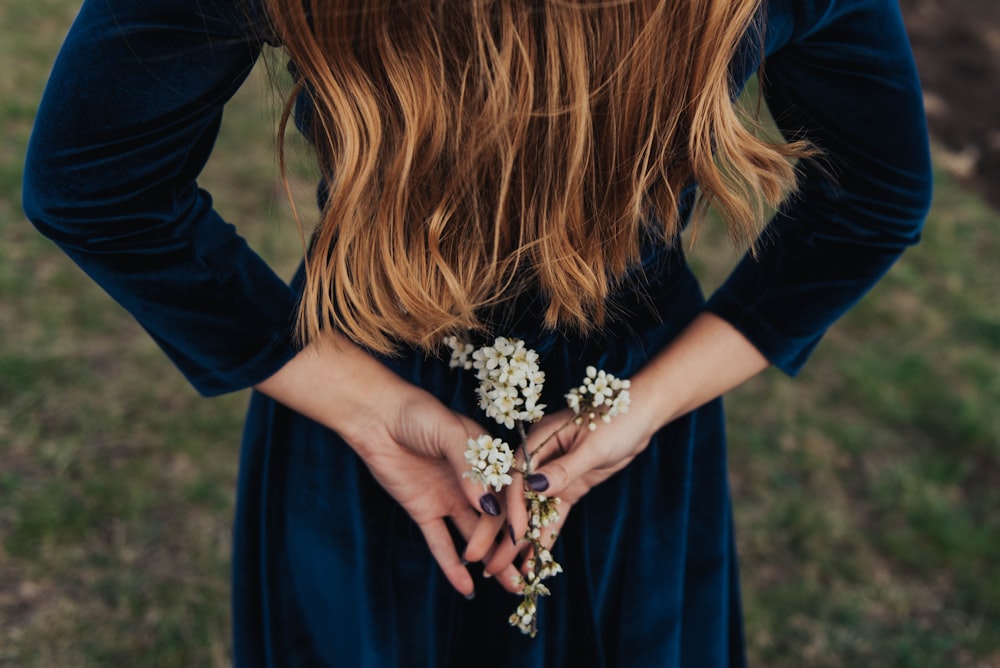 woman wearing blue long-sleeved shirt holding white flower