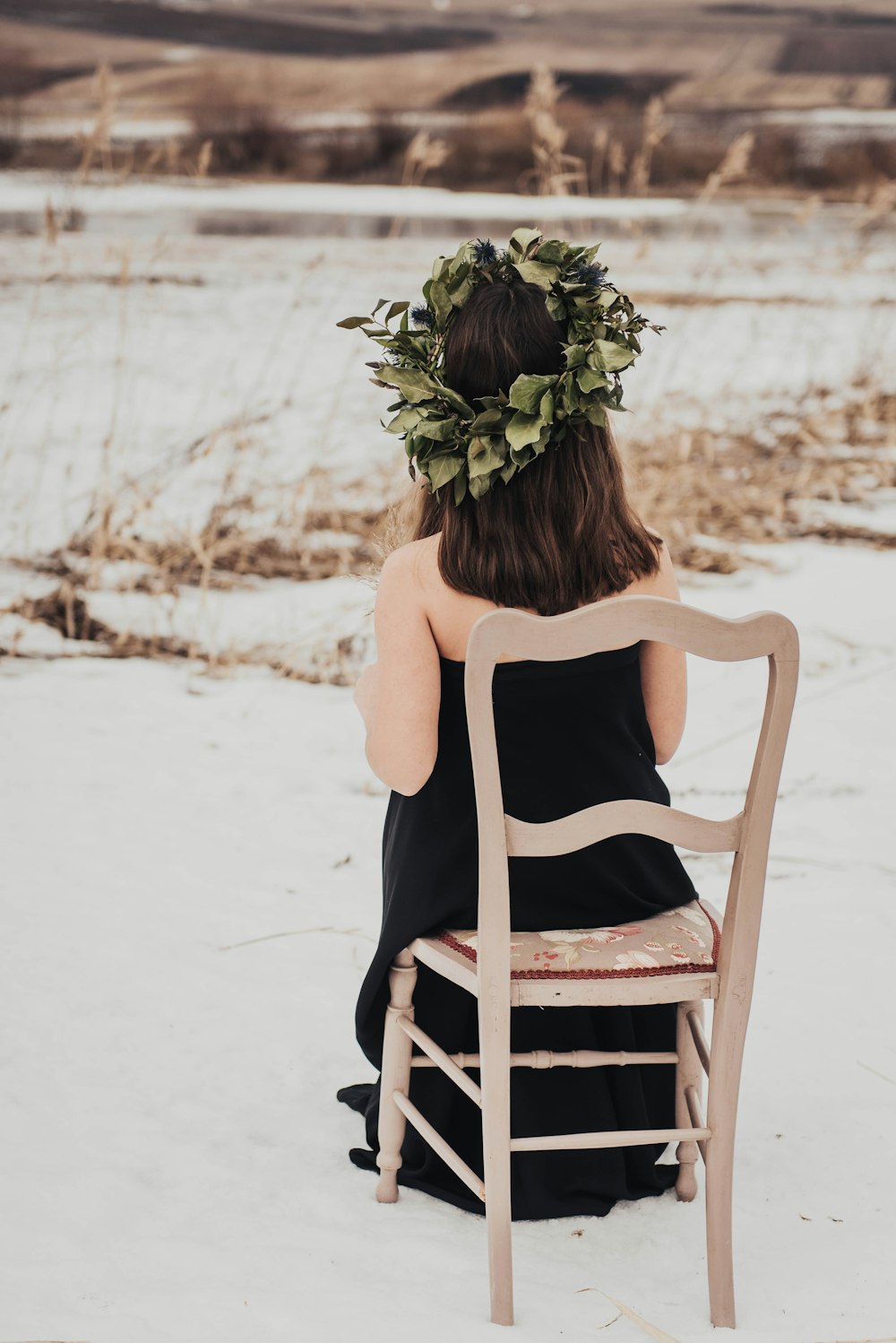 toddler wearing black tube dress sitting on brown wooden chair