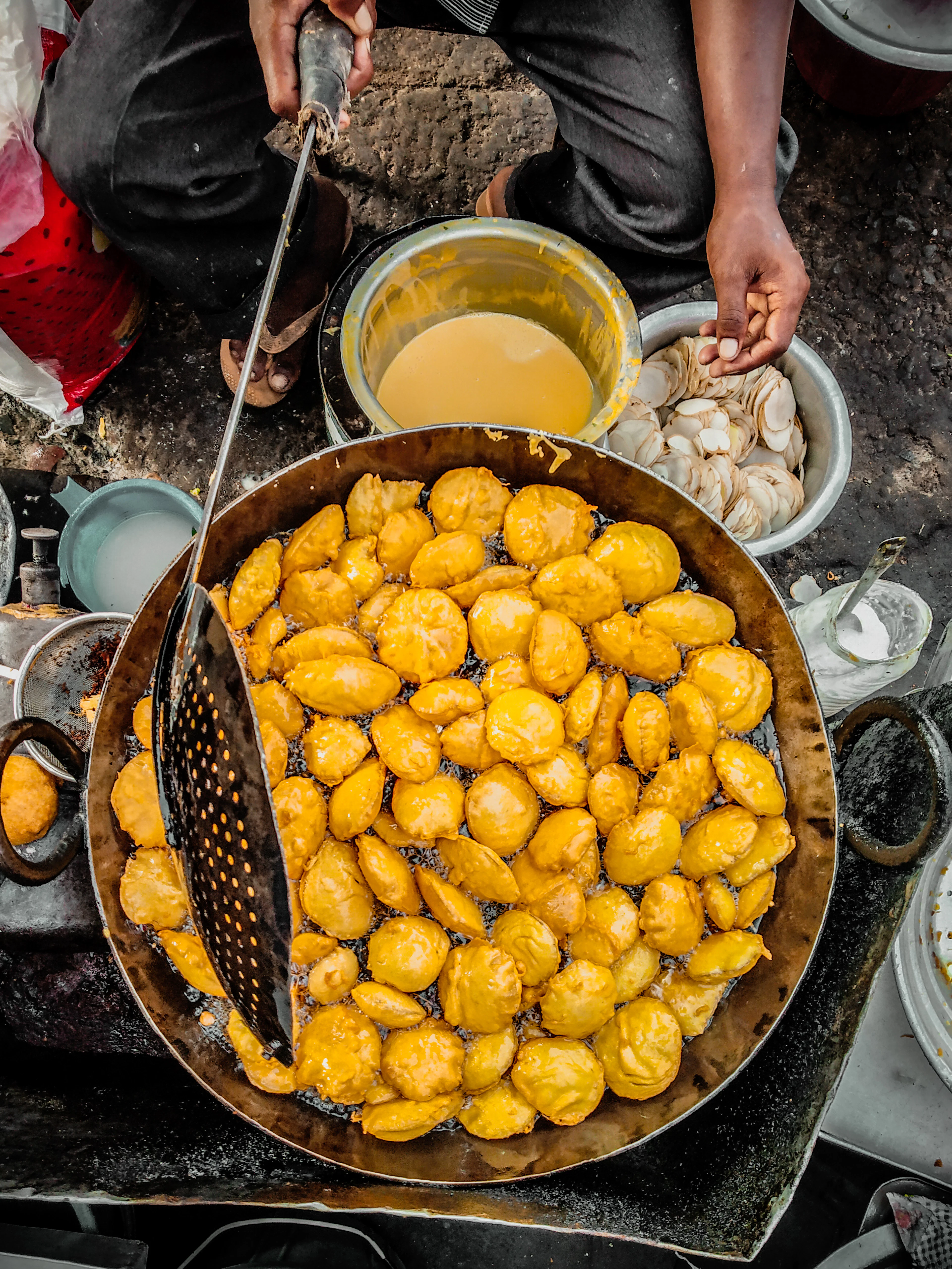Batter-coated fritters frying golden in a wide iron kadhai