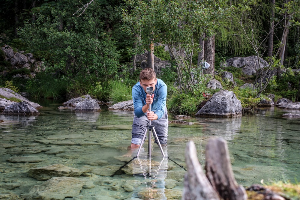 man taking a photo while standing on river