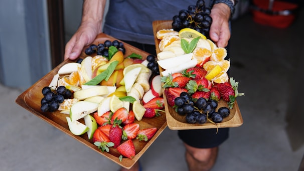 a person holding two trays of fruits