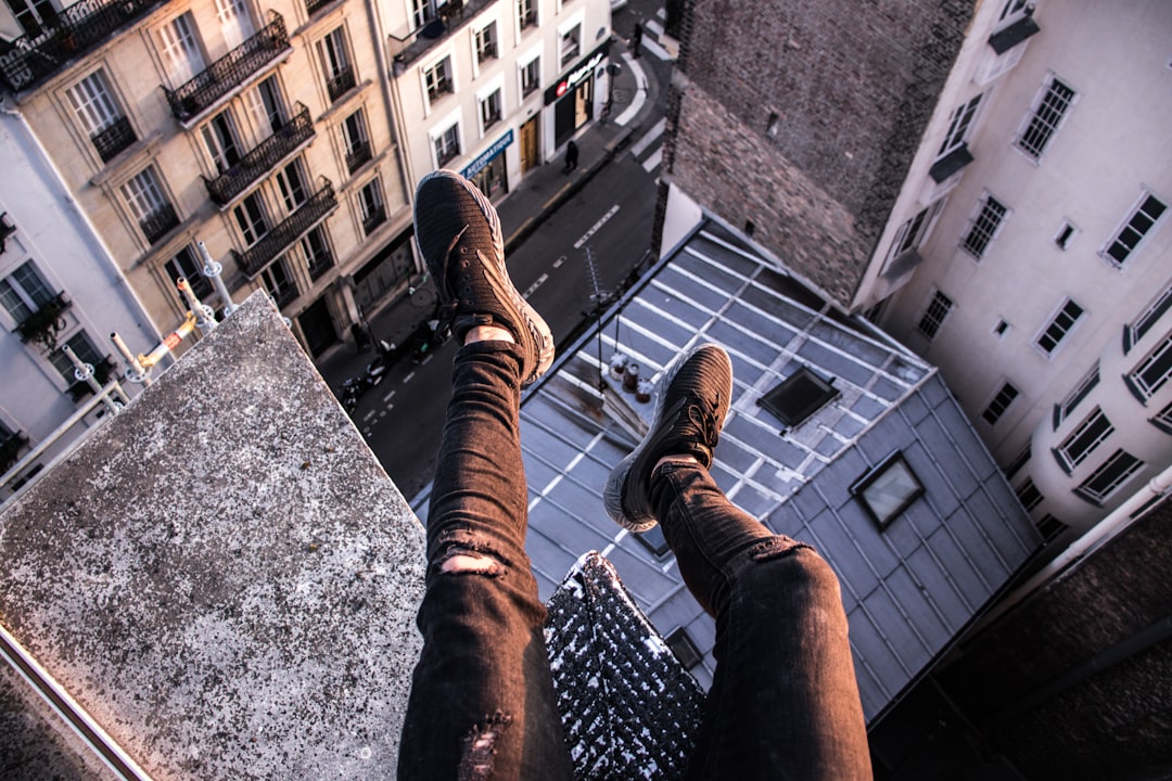 person sitting above building edge,
