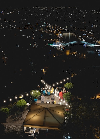 A chic rooftop terrace in a historic European city with twinkling evening lights.