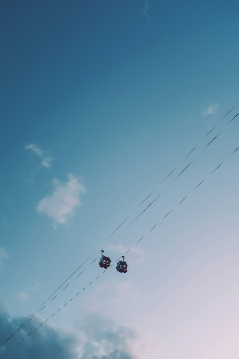 a couple of gondolas hanging from a wire in the sky