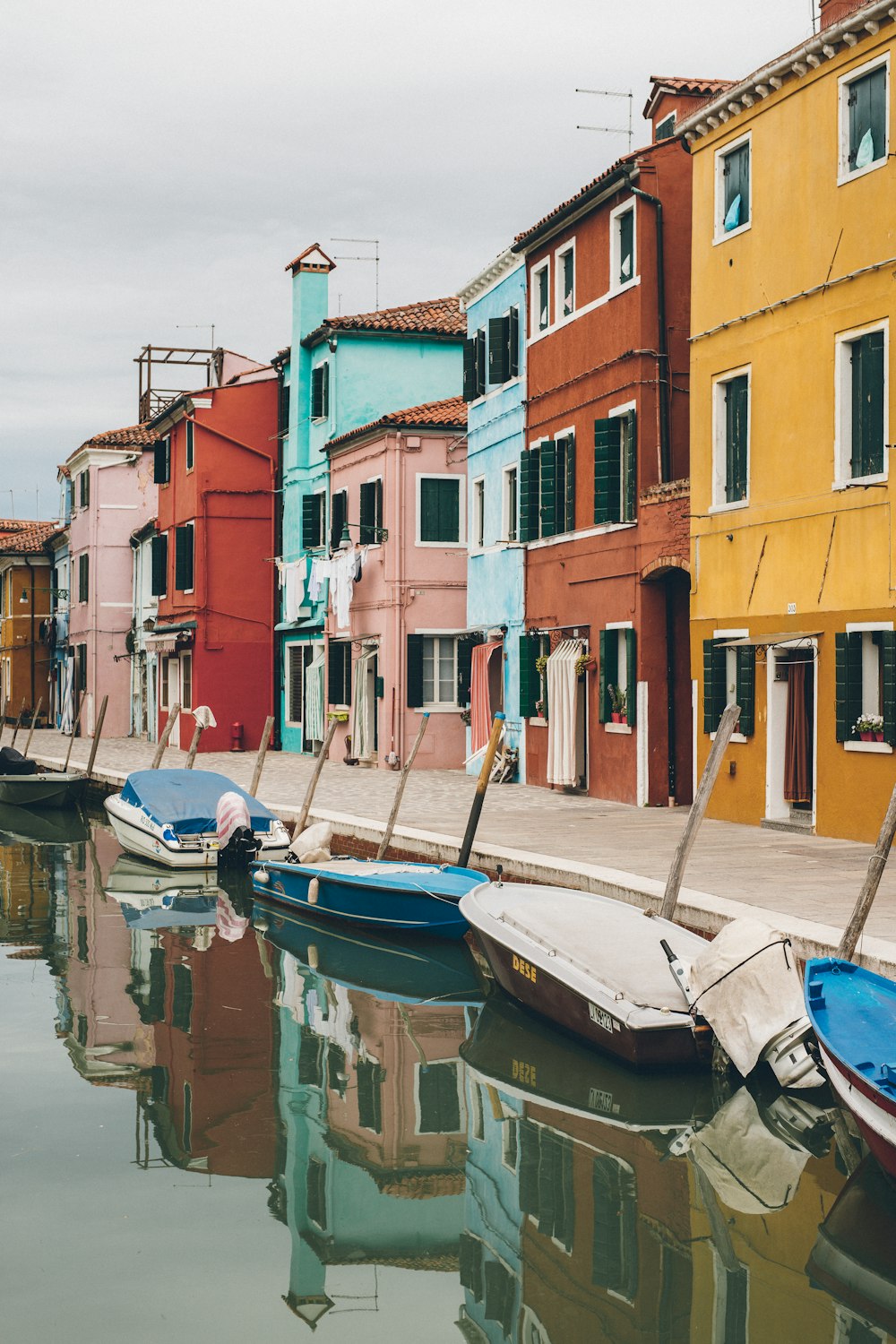 boats on calm body of water beside buildings