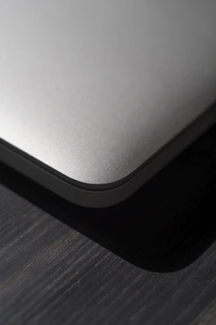 A close-up shot of a sleek laptop available for rent, resting on a wooden desk with soft natural light.
