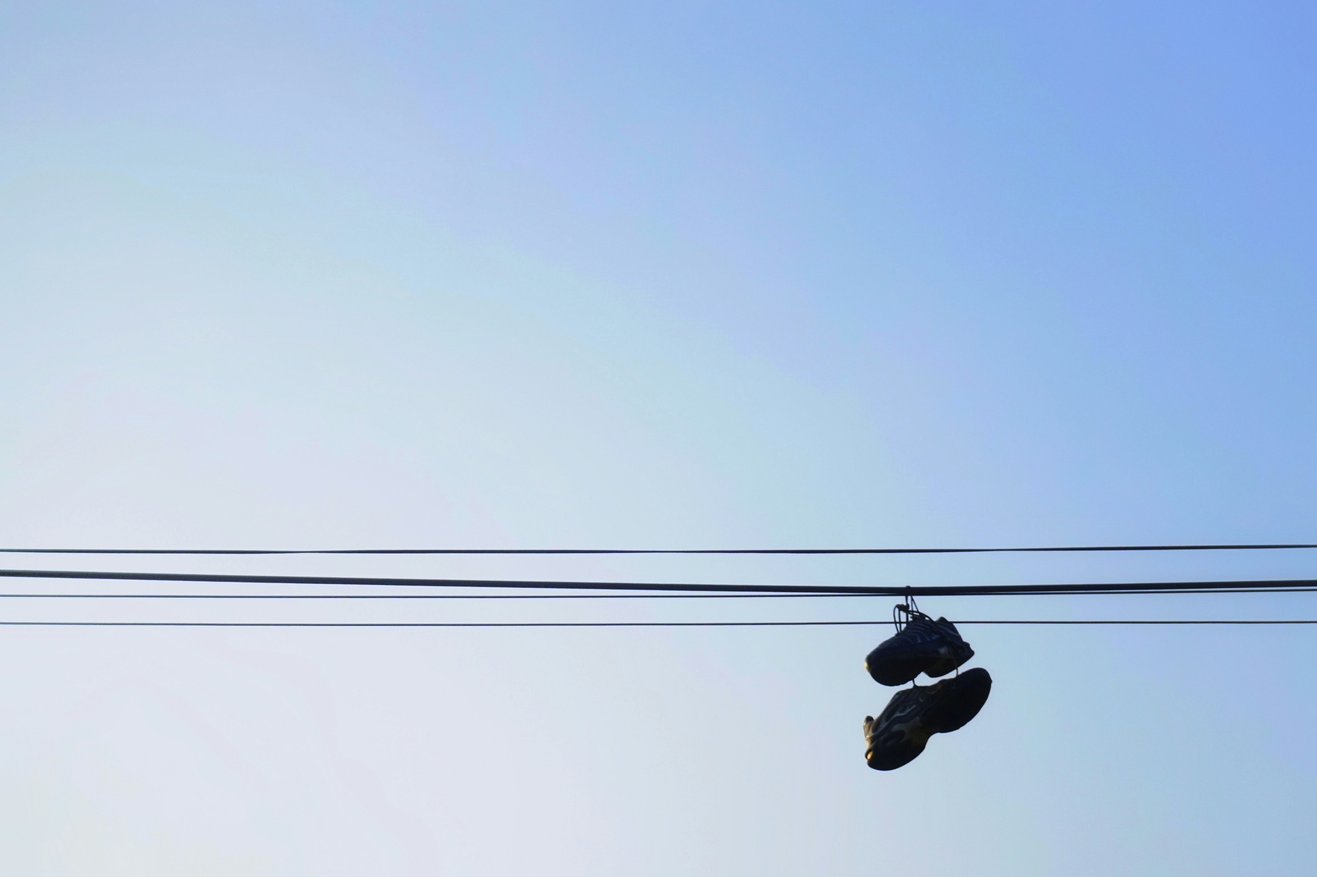 silhouette of pair of shoes hanging on wire