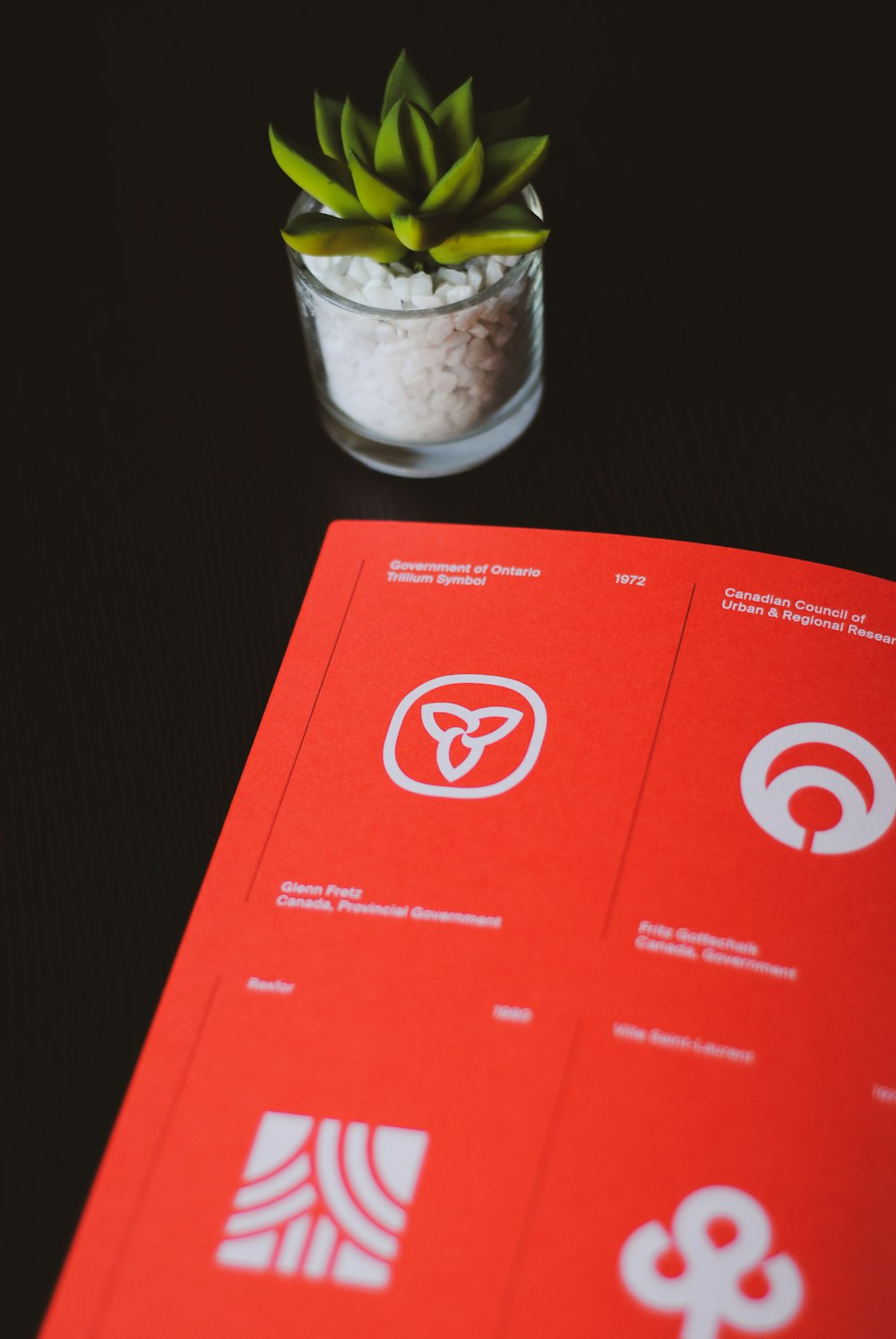 a red book sitting on top of a table next to a potted plant